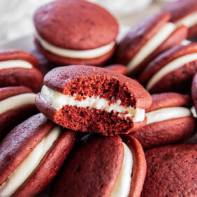 red velvet whoopie pie with a bite taken out of it sitting on top of more whoopie pies.
