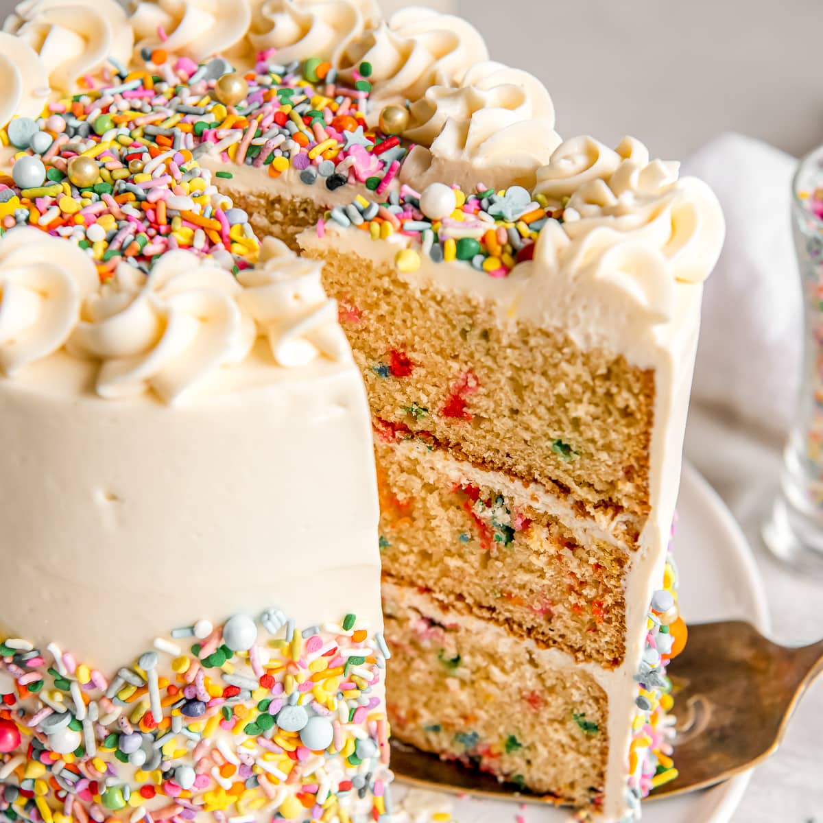 slice of triple layer funfetti cake pulled out of cake with sprinkles.