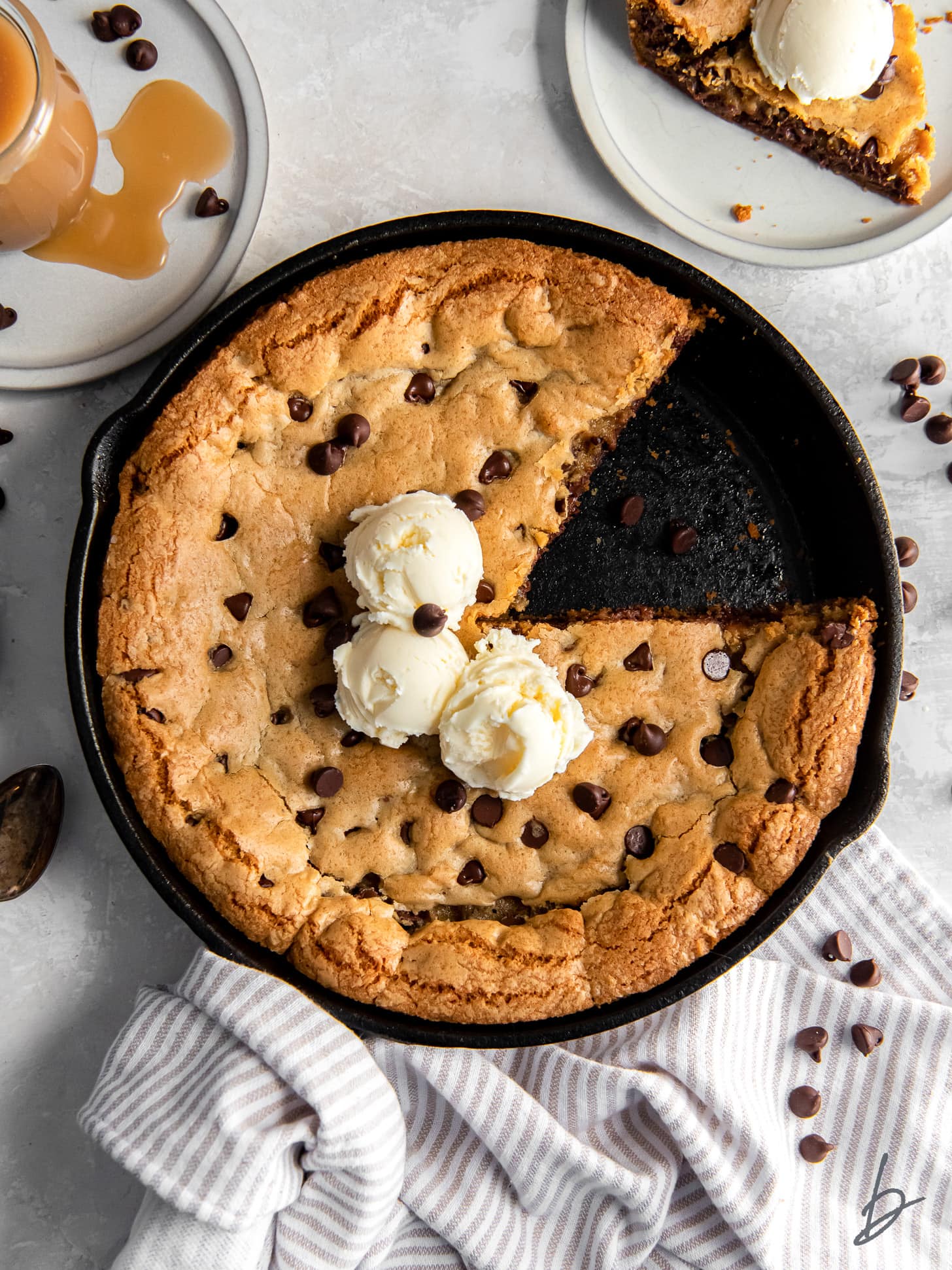 skillet chocolate chip cookie with a slice taken out and three scoops of vanilla ice cream in the center.
