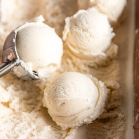 scoops of vanilla ice cream on top of ice cream in container.