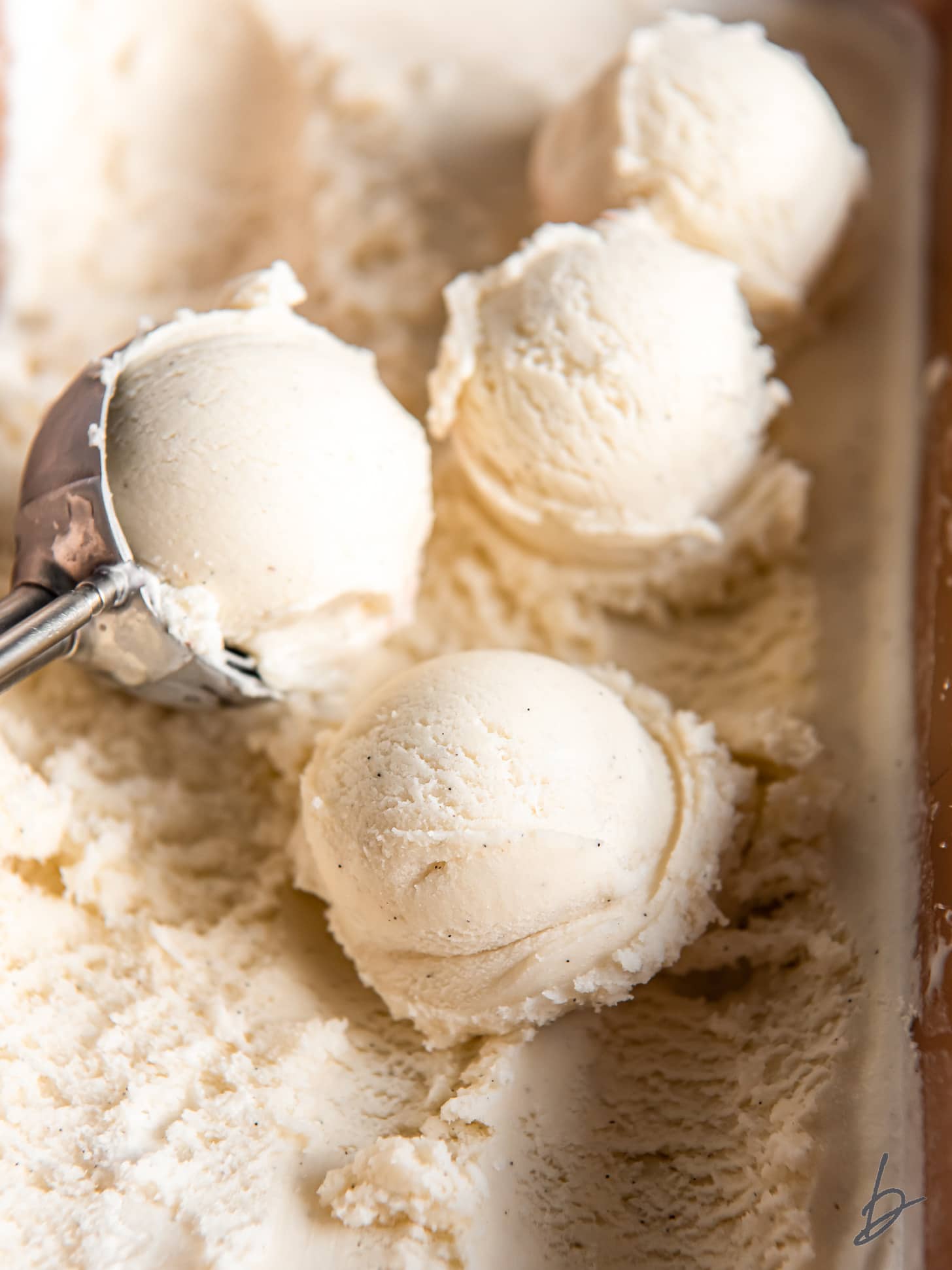 scoops of vanilla ice cream on top of ice cream in container.