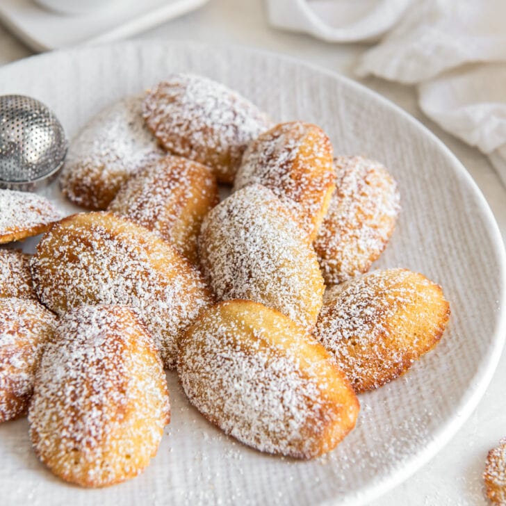 plate of madeleine cookies dusted with confectioners' sugar.