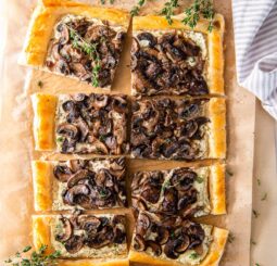 mushroom tart with goat cheese and puff pastry cut into squares on parchment paper.