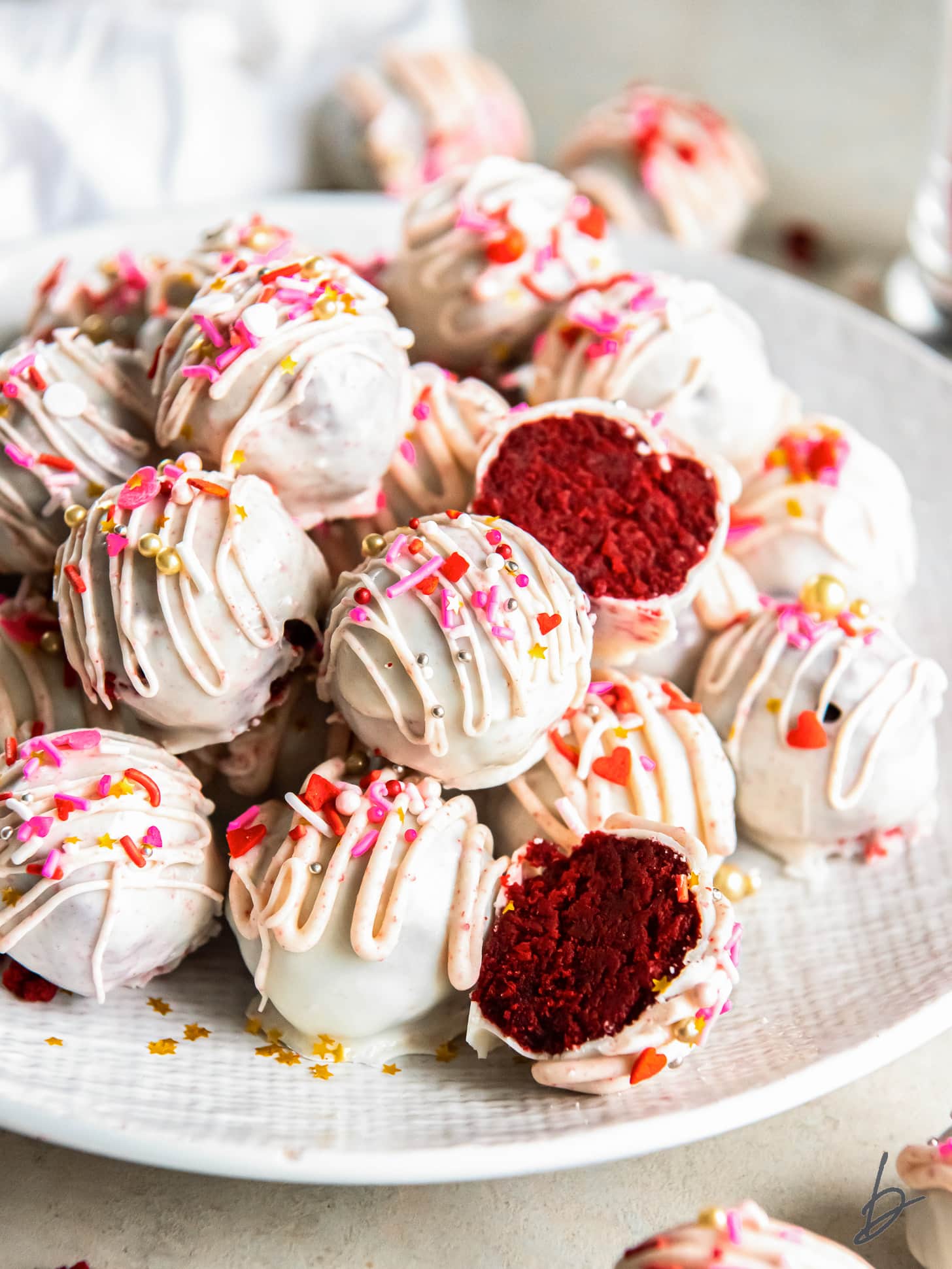 red velvet cake ball cut in half on top of more truffles on a plate.