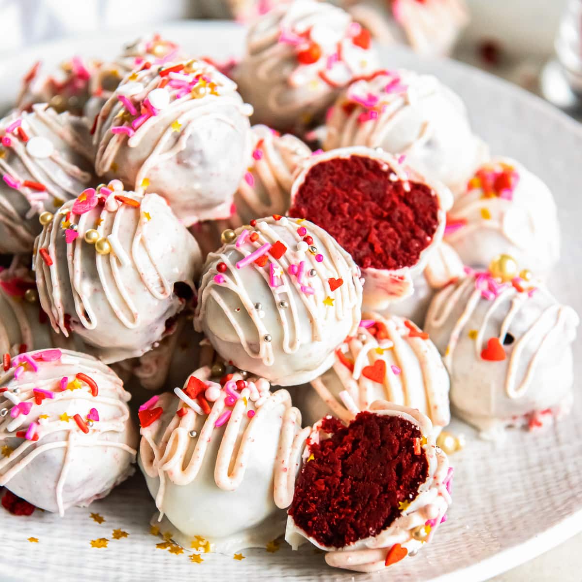 red velvet cake balls coated in white chocolate and Valentine's Day sprinkles. 