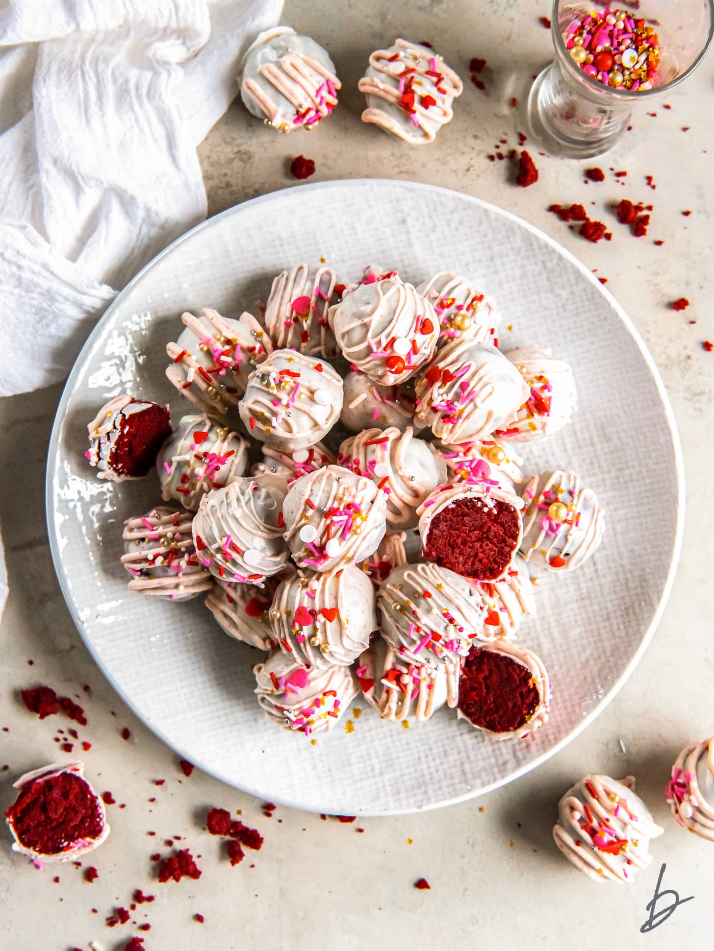 plate with red velvet cake truffles coated in white chocolate and decorated with sprinkles.