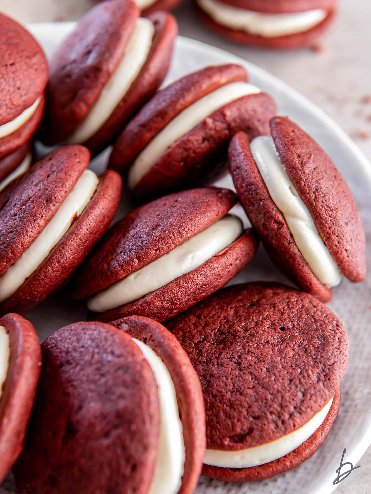 several red velvet whoopie pies with cream cheese filling.