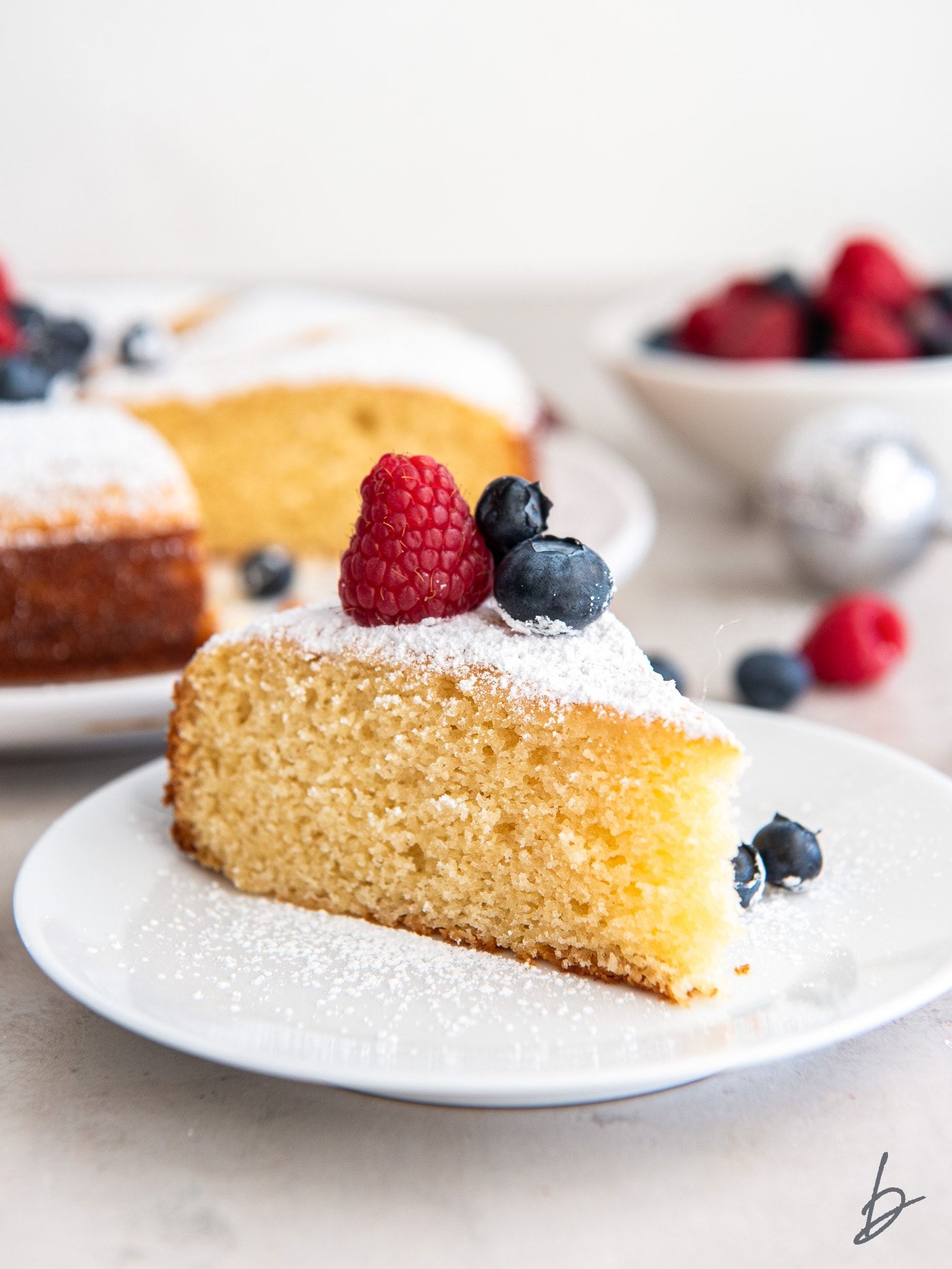 plate with slice of irish apple cake with berries on top.