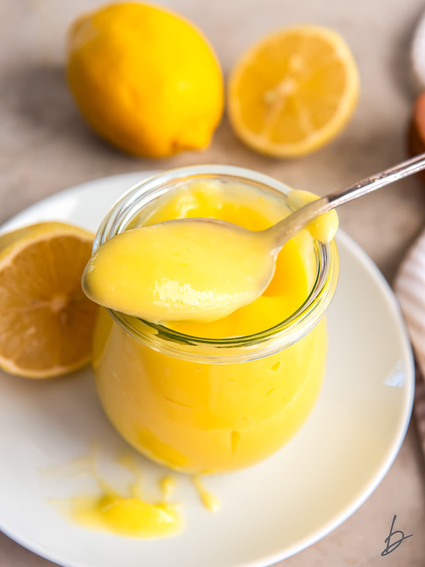 spoonful of lemon curd resting on top of glass jar filled with curd.