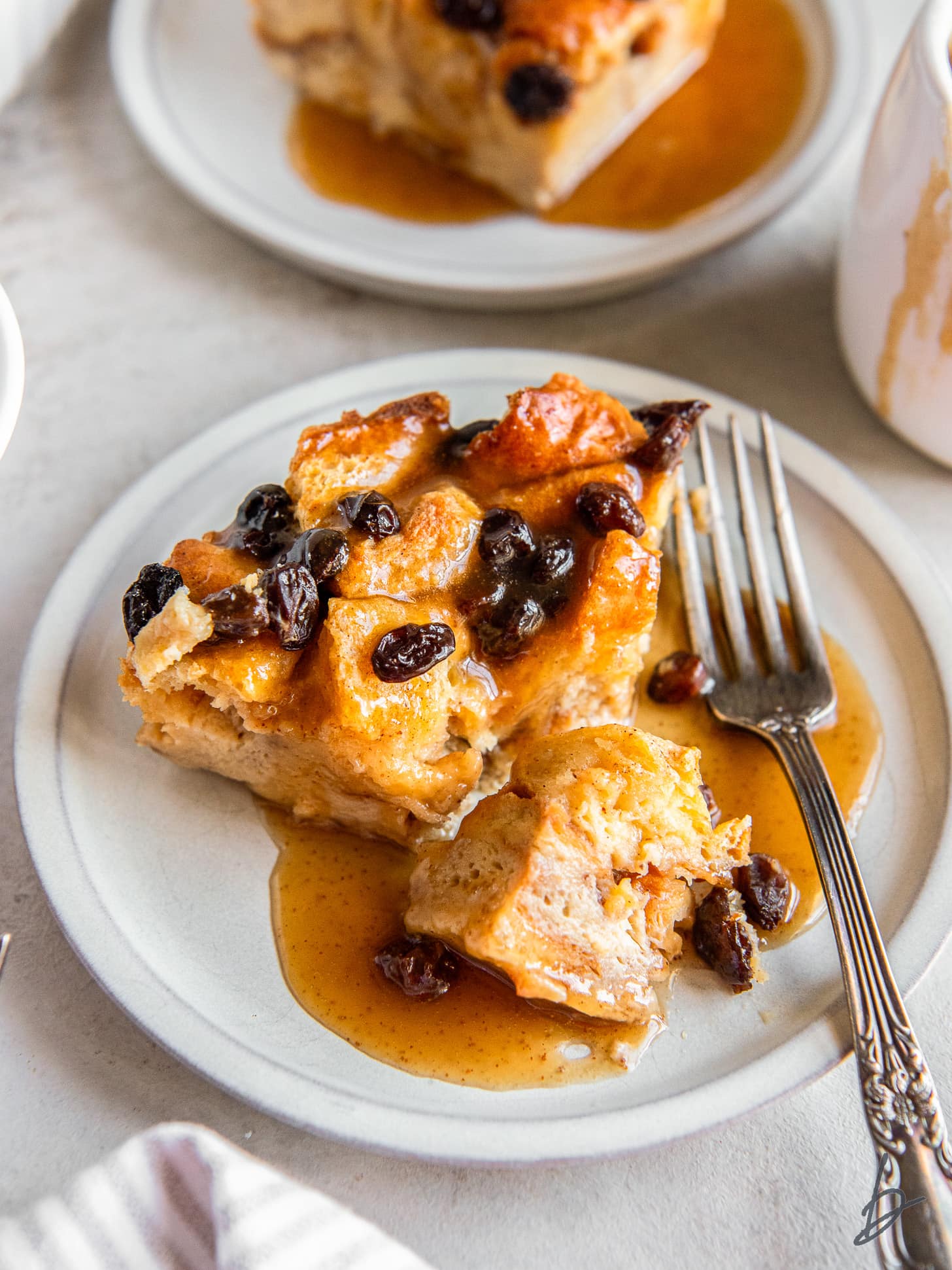 fork on a plate with slice of irish bread pudding and a piece taken off the side.