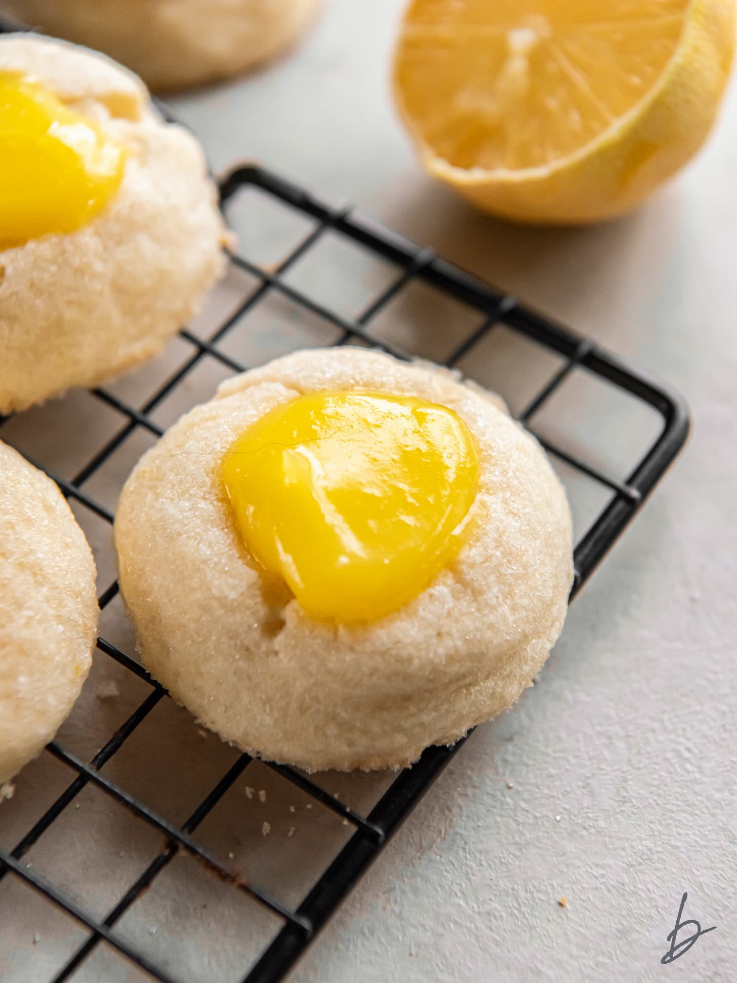 wire rack with lemon curd cookie with yellow curd in the center.