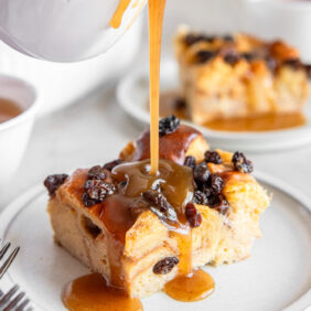 whiskey sauce poured on irish bread pudding slice with raisins.