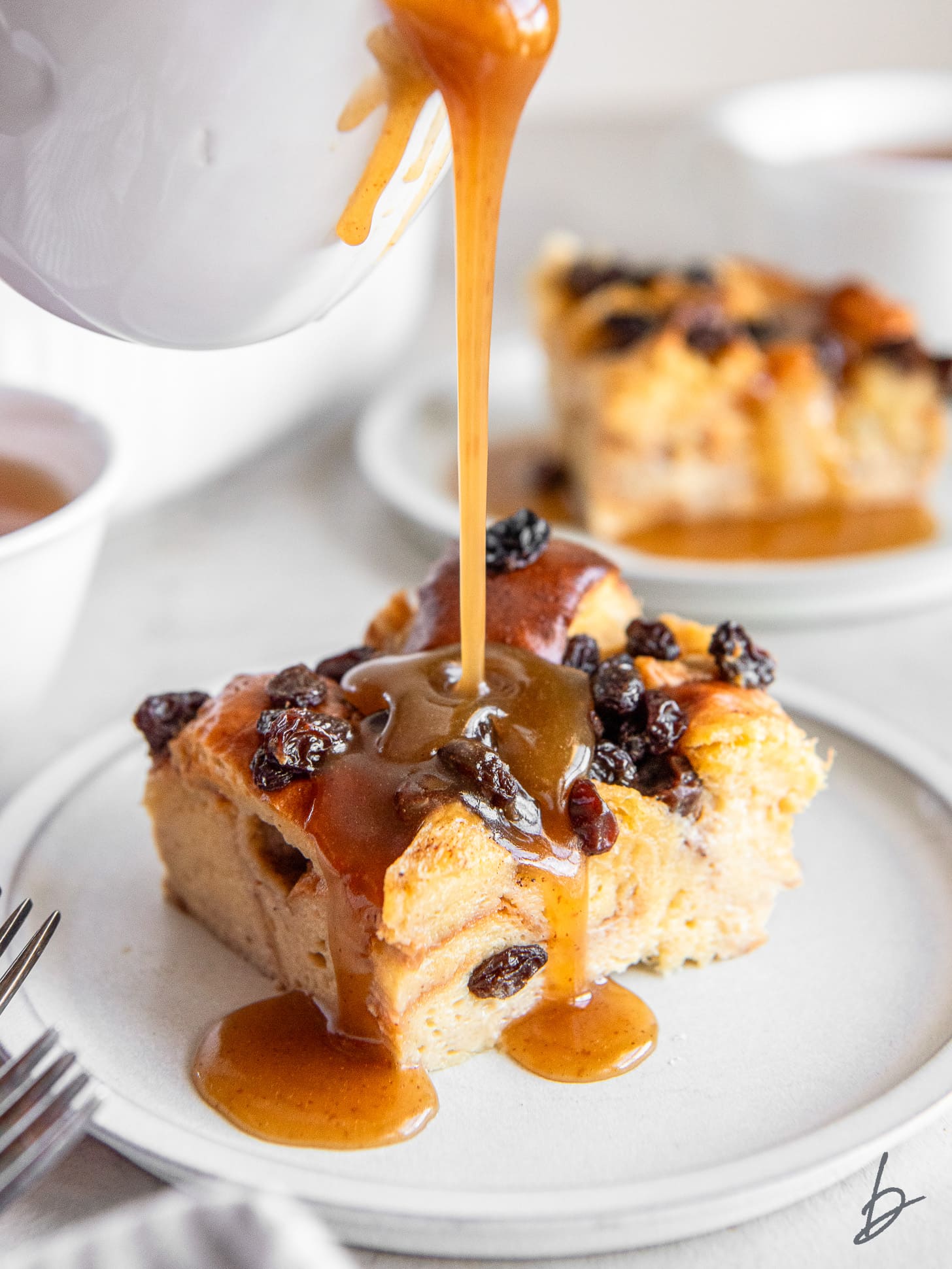 whiskey sauce poured on irish bread pudding slice with raisins.