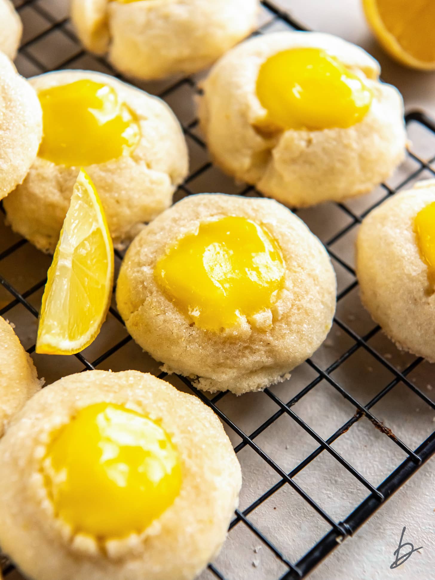 lemon curd cookie next to lemon wedge and more cookies filled with curd.