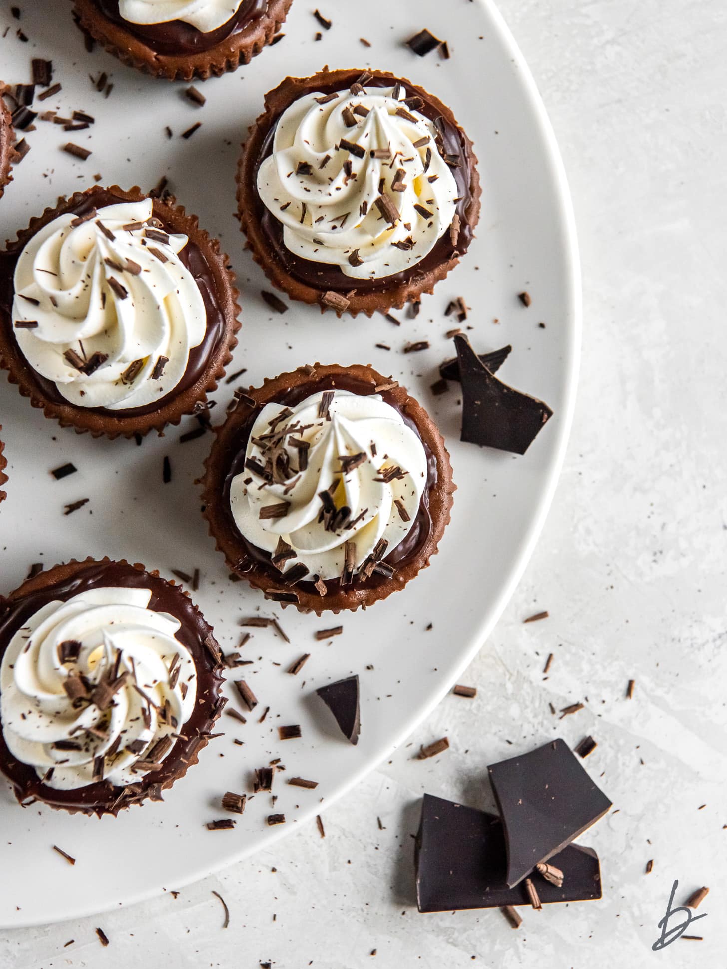 mini chocolate cheesecakes on a plate with some chopped chcolate.