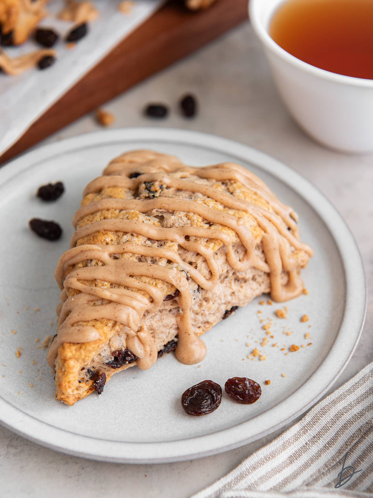 cinnamon raisins scone with cinnamon glaze on a white plate with a few raisins.