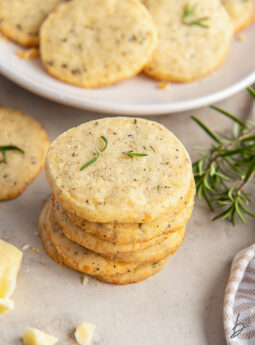 stack of savory shortbread cookies next to some fresh rosemary.
