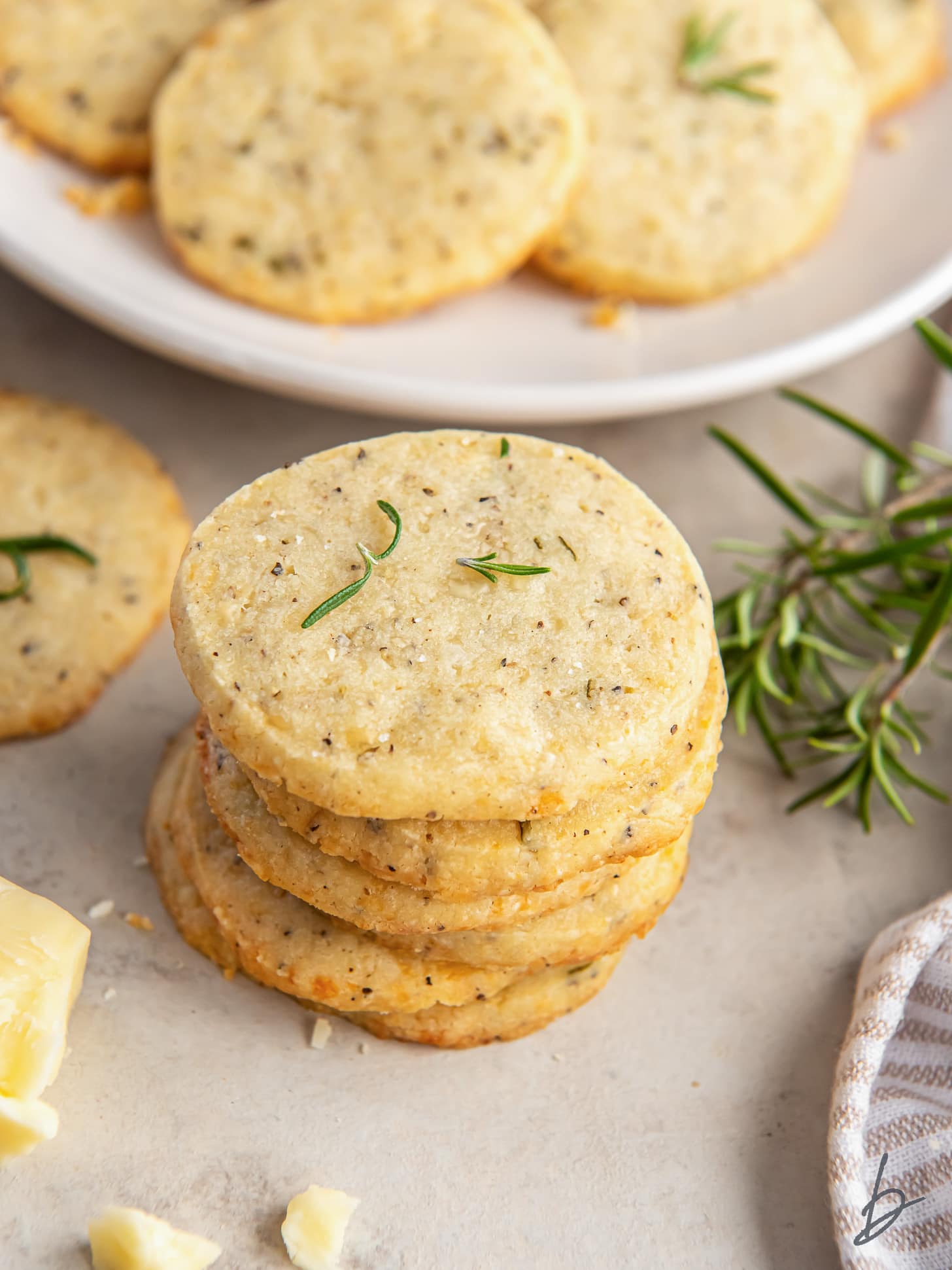 stack of savory shortbread cookies next to some fresh rosemary.