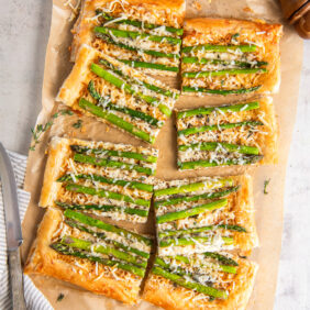 asparagus tart with puff pastry and gruyere cheese on a piece of parchment paper.