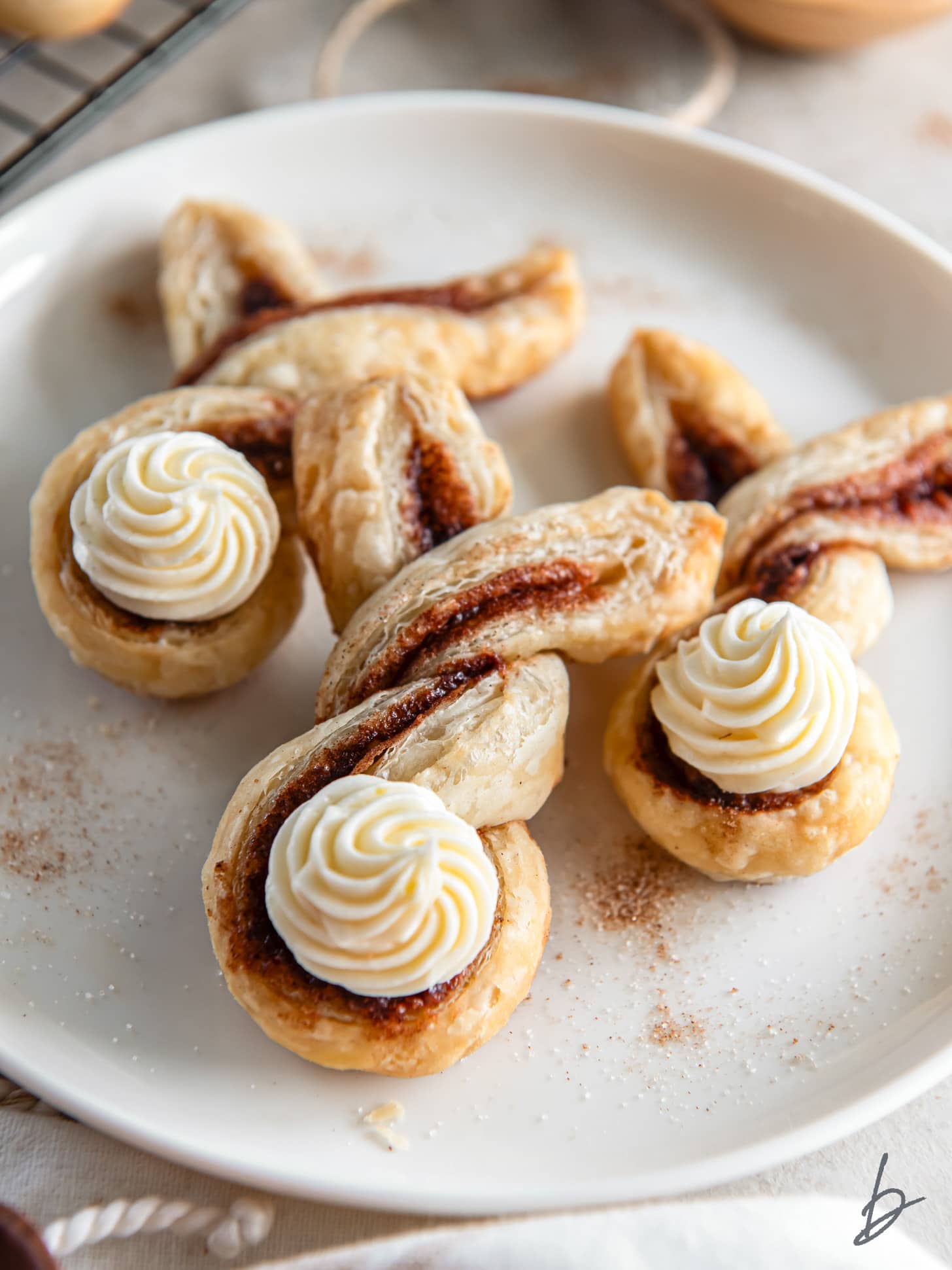 three bunny cinnamon twists on a plate with cream cheese frosting for bunny tails.