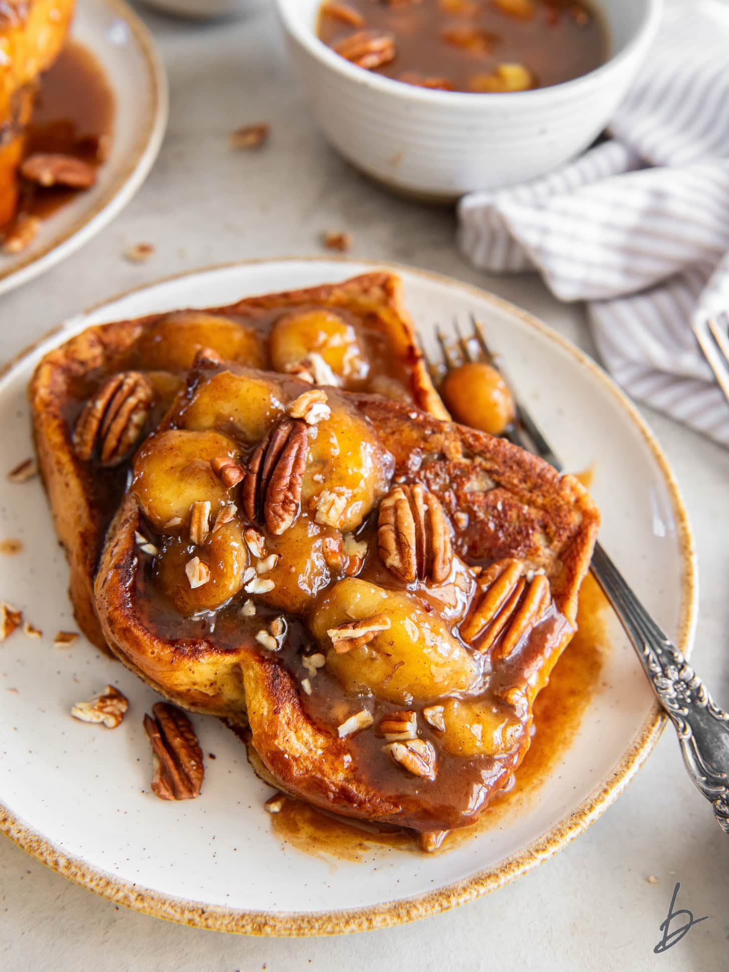 plate of french toast with caramelized bananas foster topping and pecans.