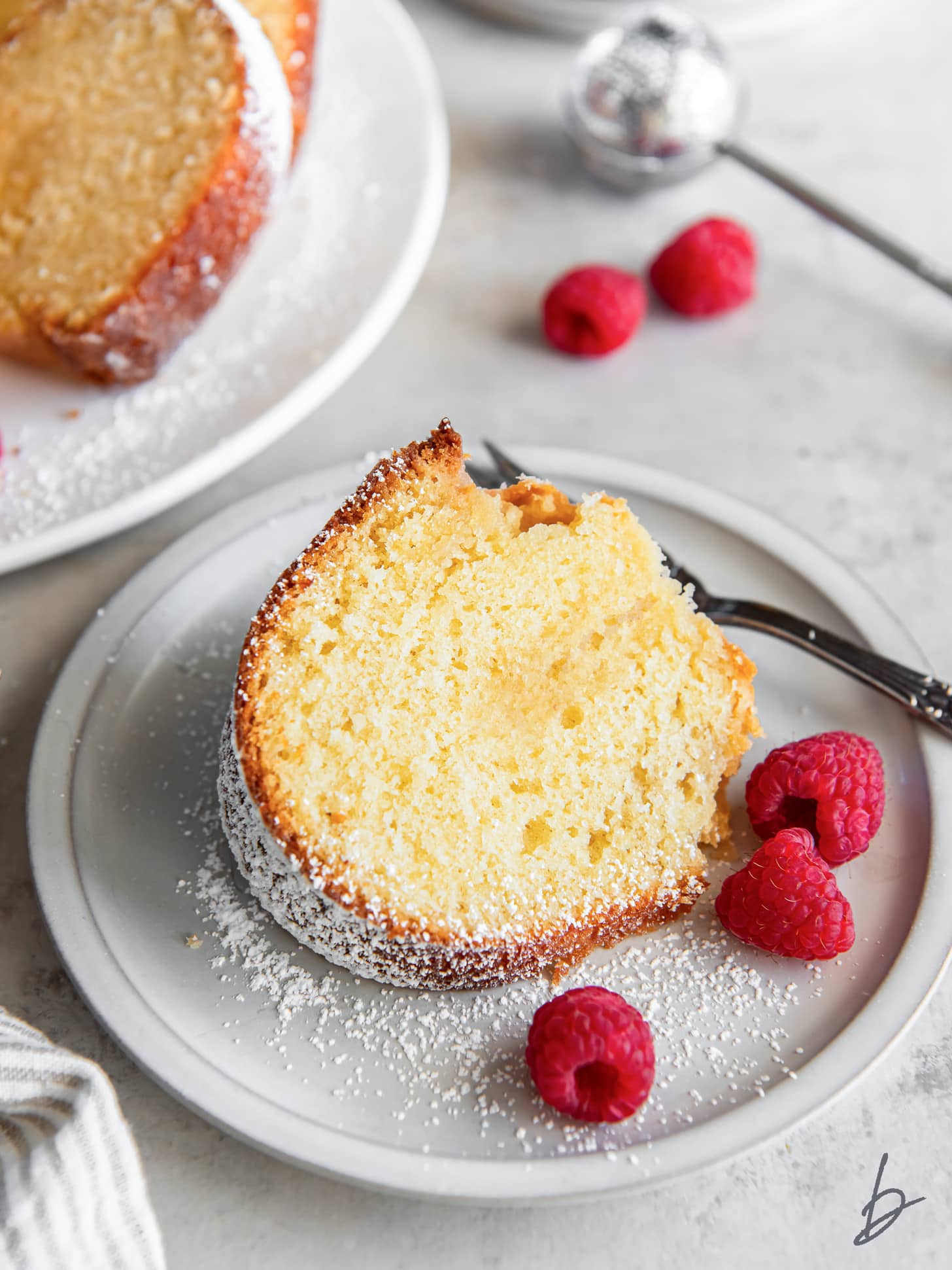 slice of kentucky butter cake on a plate with a few fresh raspberries.
