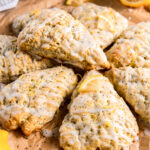 lemon poppyseed scone with glaze on top of more scones on parchment paper.