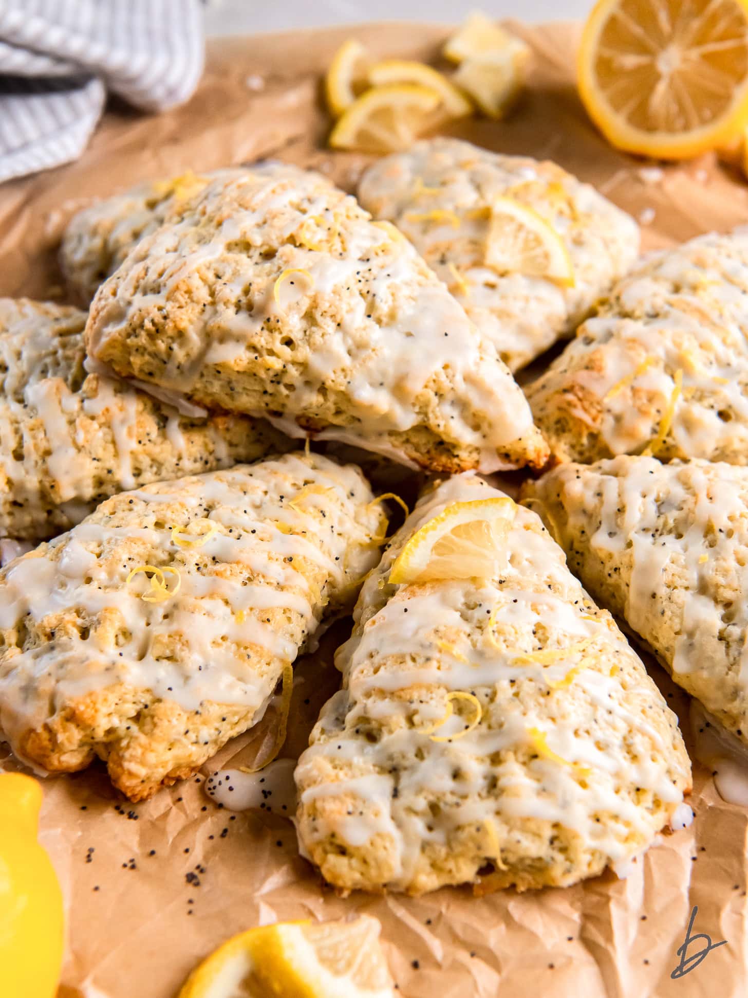 lemon poppyseed scone with glaze on top of more scones on parchment paper.