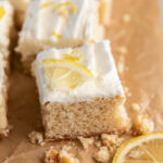 lemon sugar cookie bar with frosting and lemon zest garnish on parchment paper.