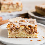 slice of honey bun cake on a plate showing layers of cinnamon brown sugar inside.