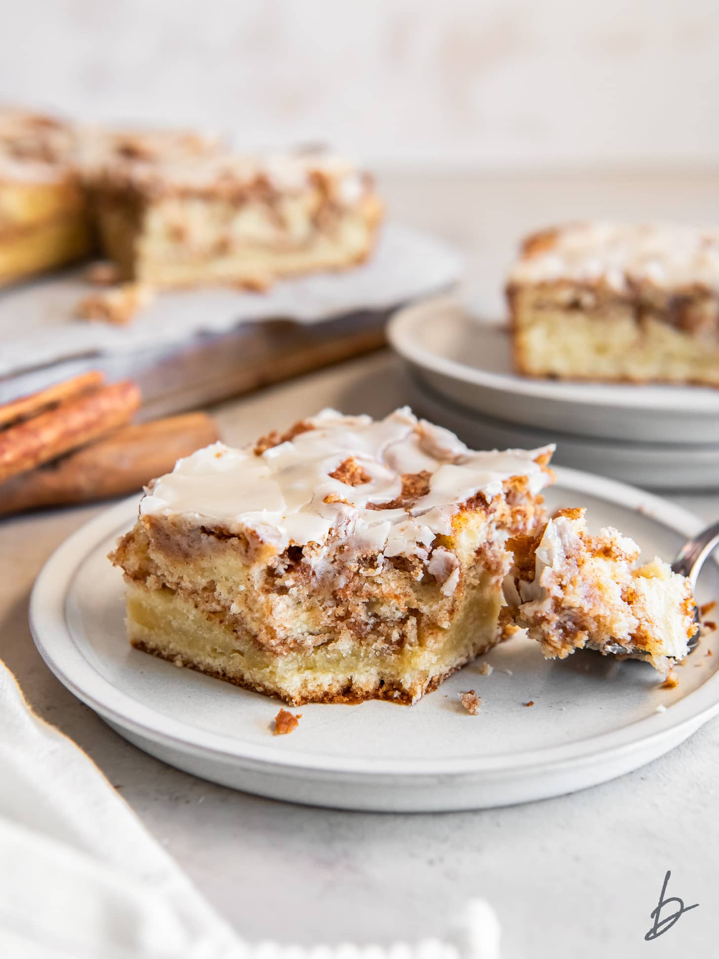 slice of moist honey bun cake on a plate with a fork holding a slice.