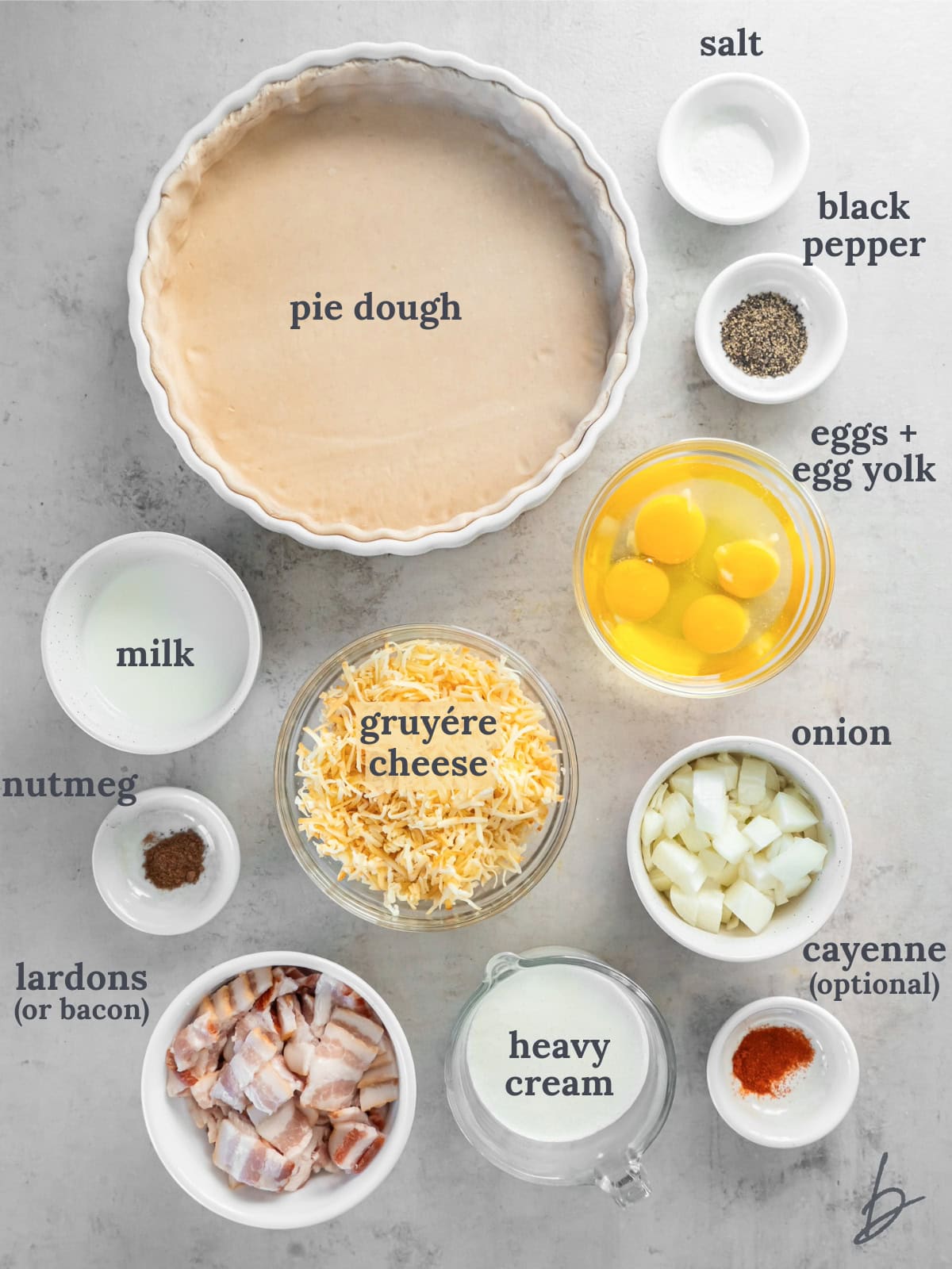 quiche lorraine ingredients in bowls on a tabletop.