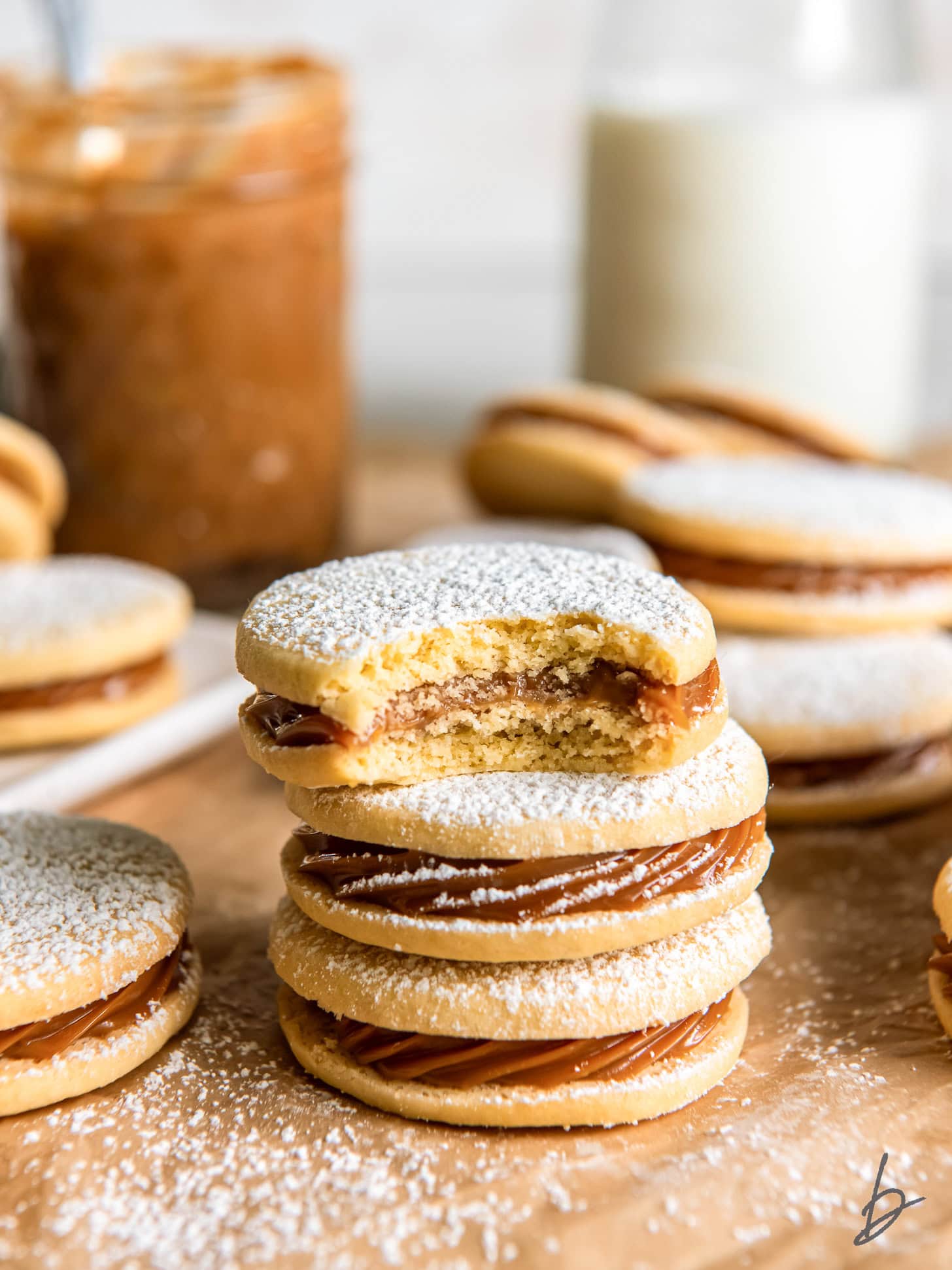 stack of dulce de leche cookie sandwiches and top cookie has a bite.
