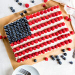 american flag cake with blueberries for stars and raspberries for stripes.