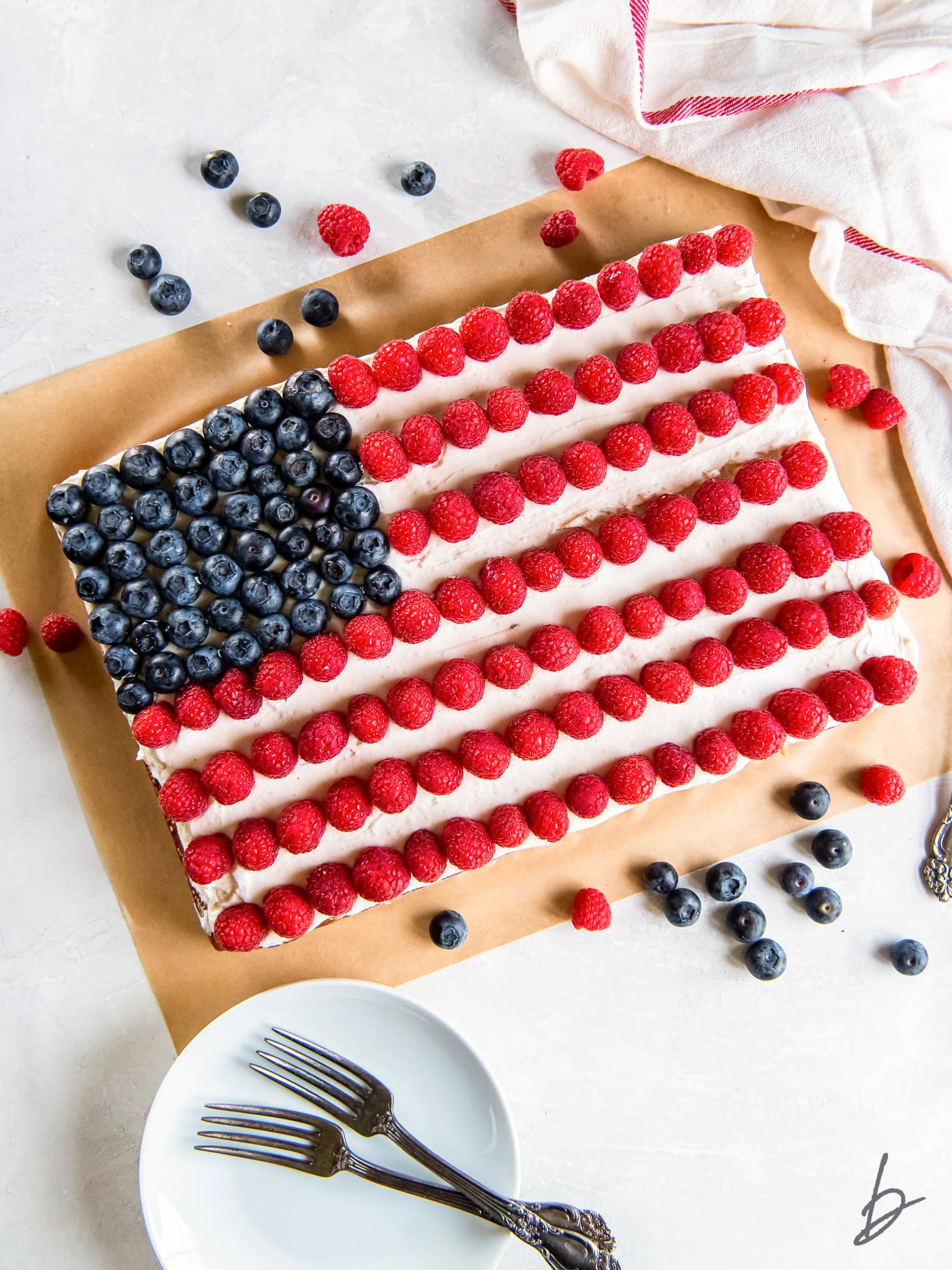 american flag cake with blueberries for stars and raspberries for stripes.