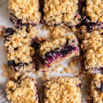 blueberry crumb bars on a tabletop with one bar on its side to show layers of filling and crumble.