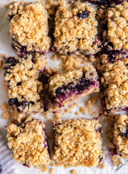 blueberry crumb bars on a tabletop with one bar on its side to show layers of filling and crumble.