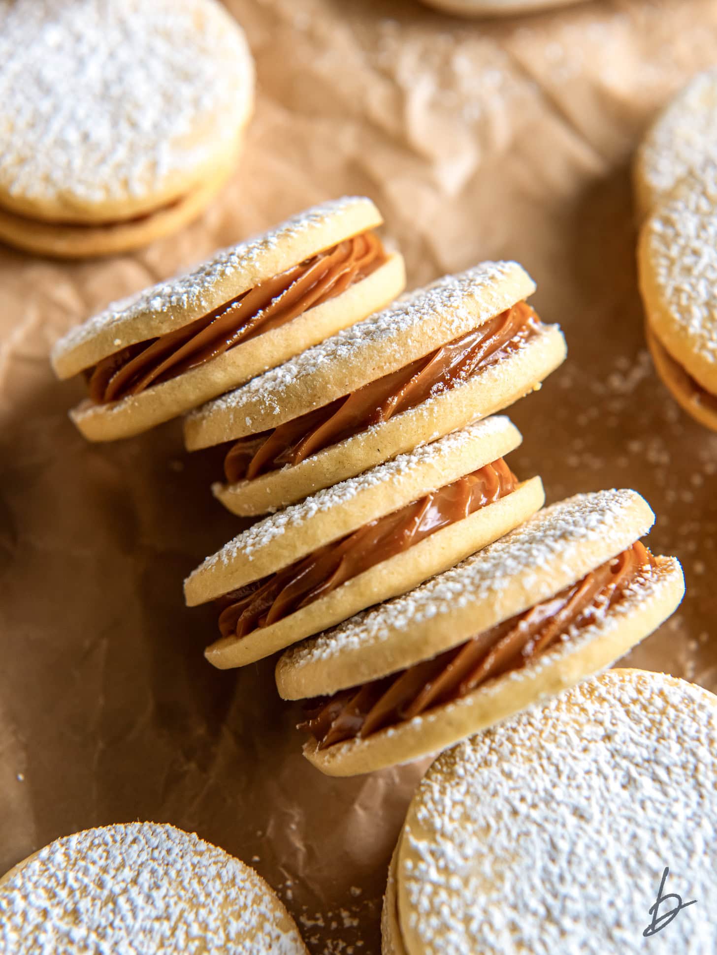 four dulce de leche sandwich cookies on their side showing filling inside.