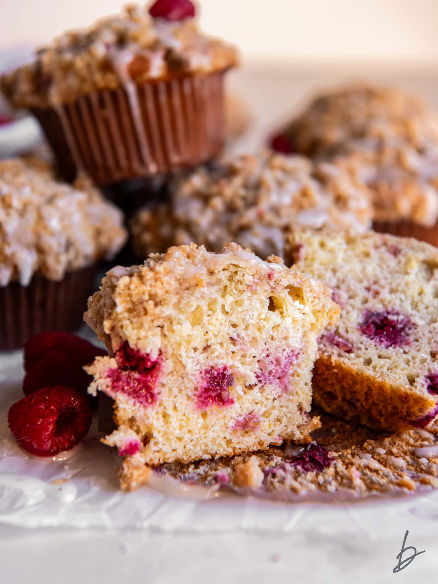 raspberry muffin cut in half showing berries inside and streusel on top.