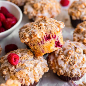 raspberry muffin with streusel on top of two more muffins.