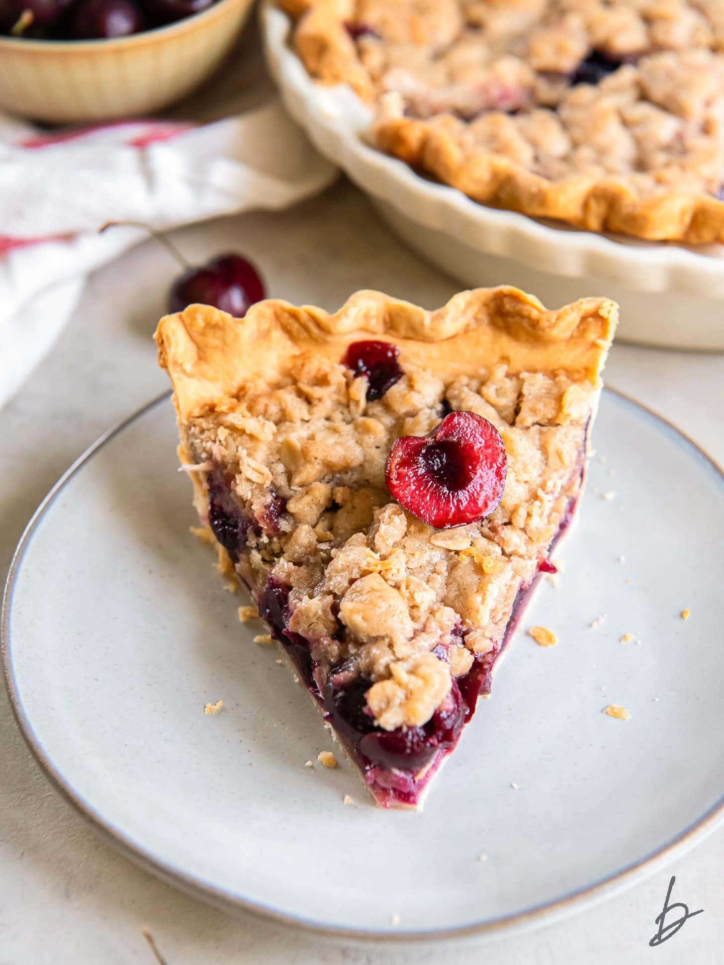 slice of cherry crumb pie on a round plate.