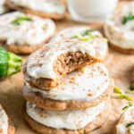 stack of frosted zucchini cookies with top cookie with a bite.