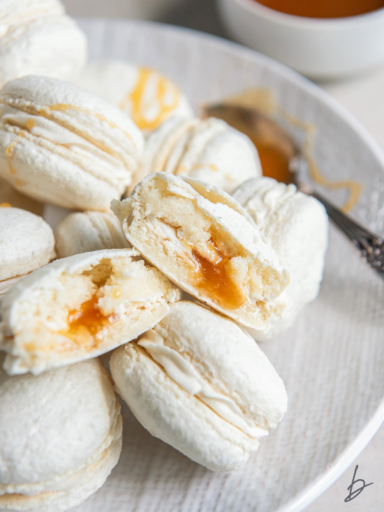 salted caramel macaron with a bite taken out of it to show caramel filling.