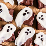ghost brownies on parchment paper with white chocolate ghosts on top of brownies.