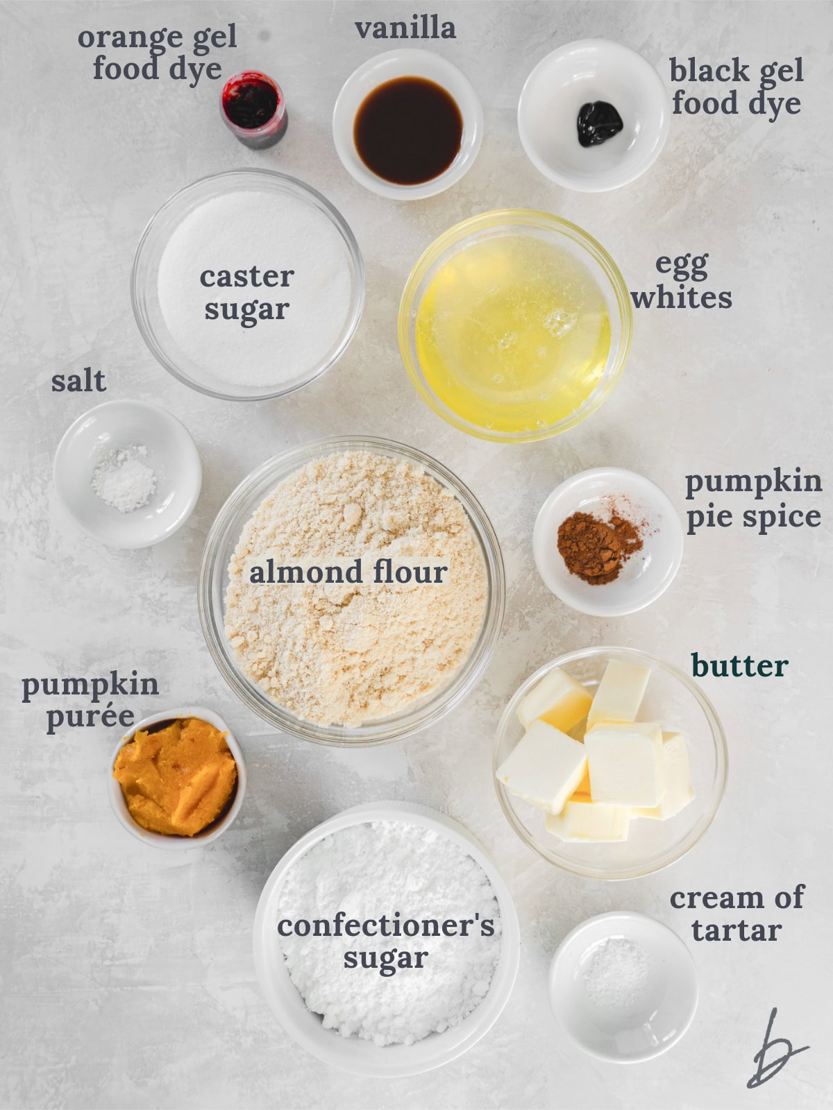 tabletop with bowls of ingredients to make pumpkin spice macarons.