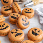 pumpkin spice macarons decorated to look like jack-o-lanterns.