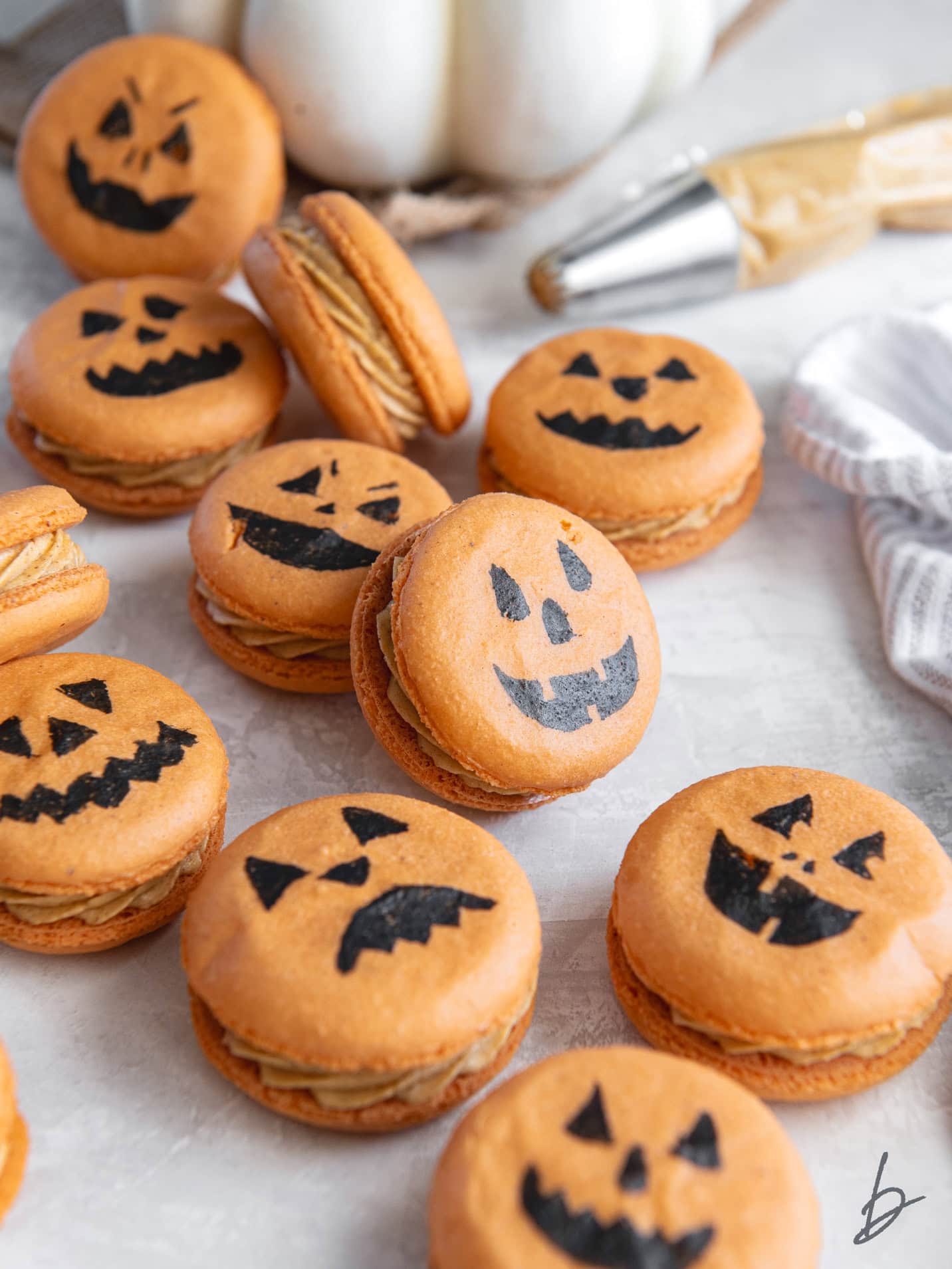pumpkin spice macarons decorated to look like jack-o-lanterns.