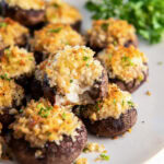 plate of boursin stuffed mushrooms with top mushroom with a bite taken out of it.