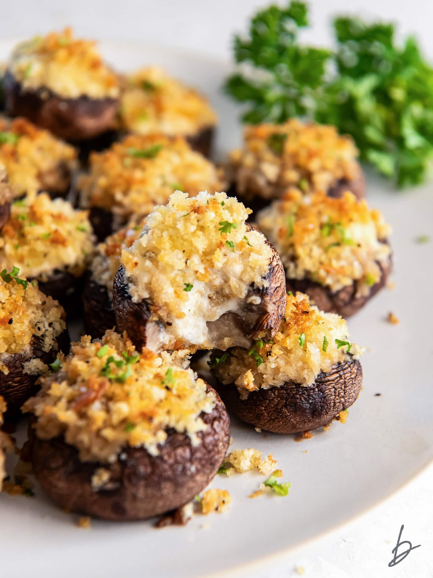 plate of boursin stuffed mushrooms with top mushroom with a bite taken out of it.