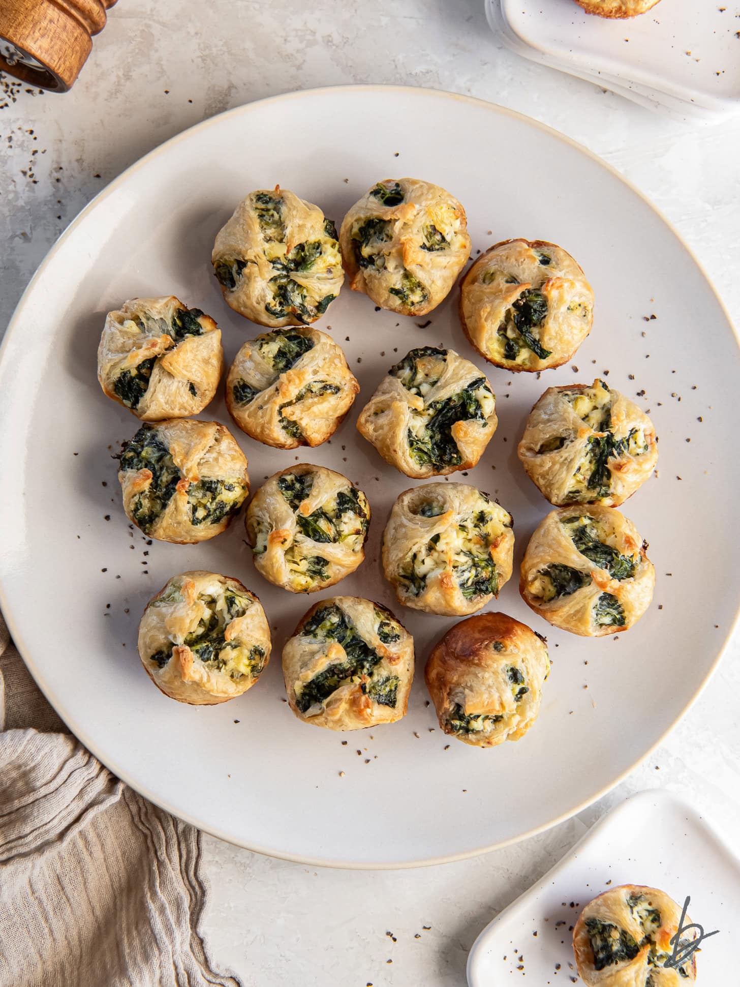 spinach puffs on a white round plate on a tabletop.